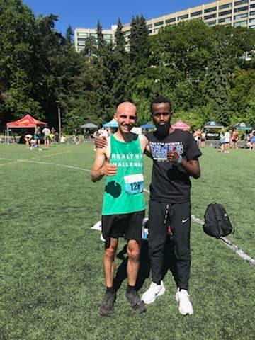 Luke posing with a thumbs up in his green HEALTHY CHALLENGE racing top with his friend Ahmed, also giving a thumbs up.