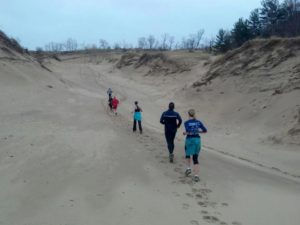 Crew running up sand dune