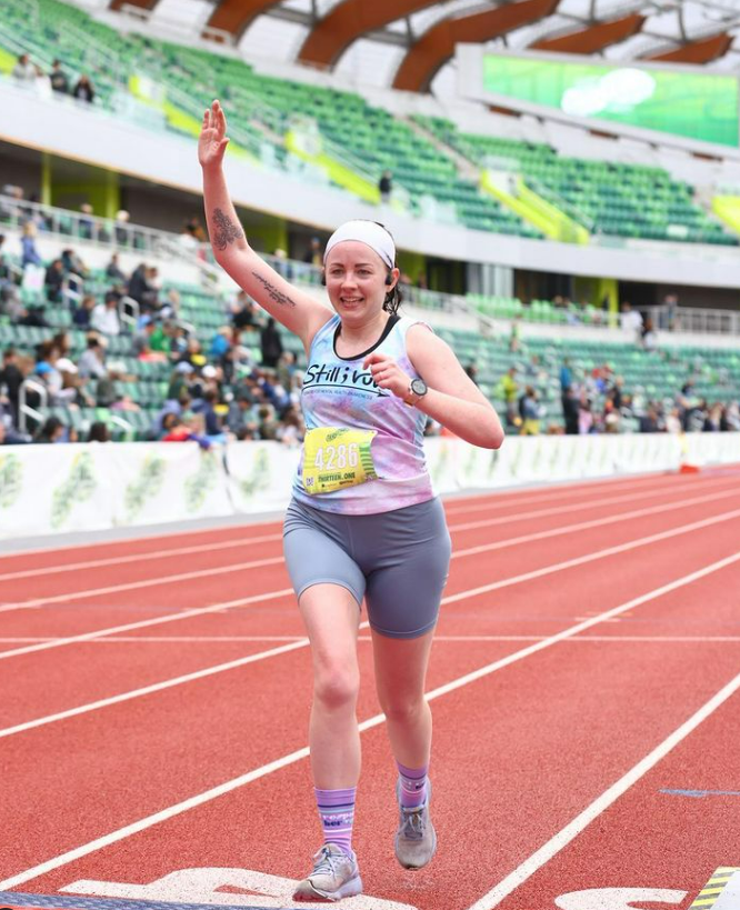 a woman running on a track with her hand in the air
