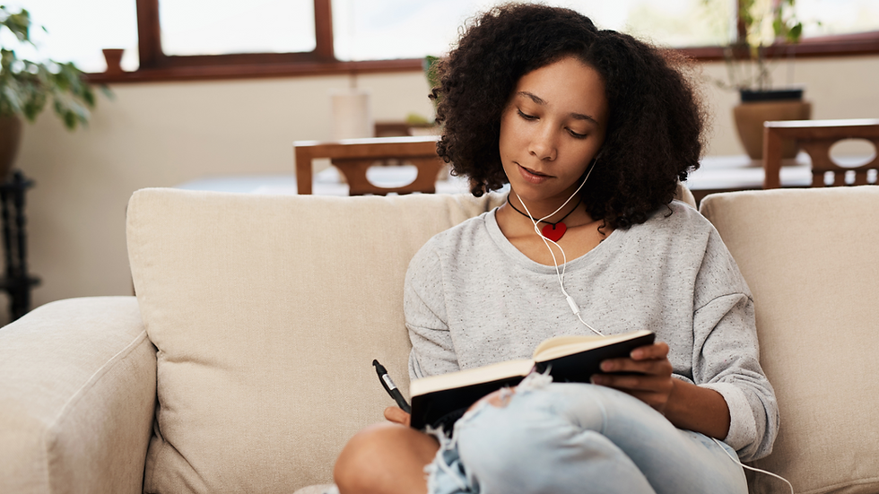 a woman sitting on a couch writing in a journal