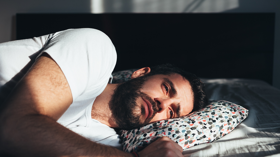 man laying in bed with a sad look on his face