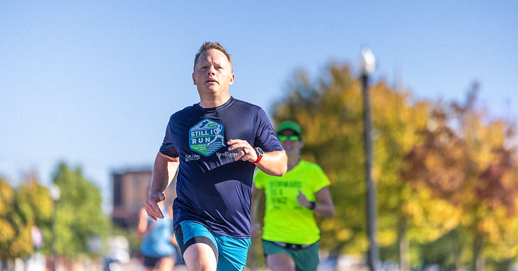 a man running wearing a Still I Run shirt